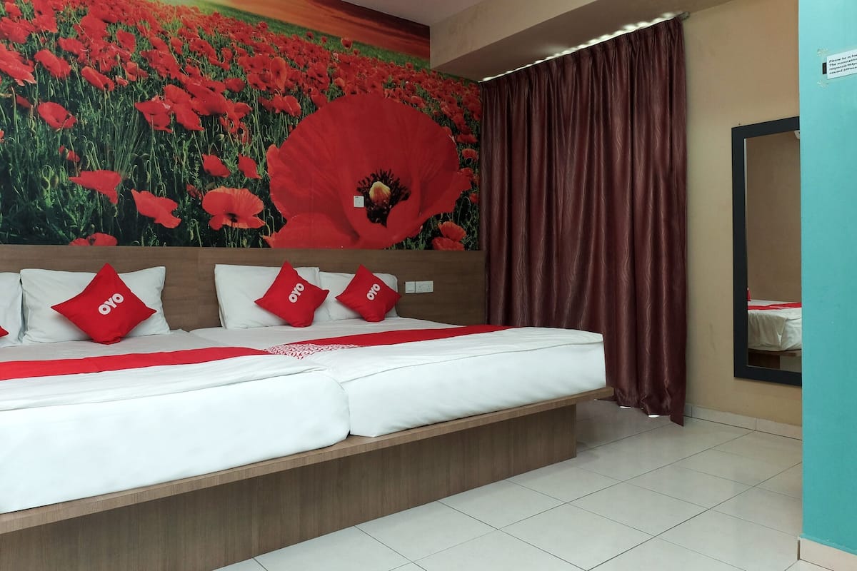 A hotel room with a large bed, red and white bedding, a poppy-themed mural, and a view of a garden through a window.