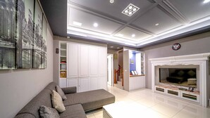 Een moderne woonkamer met een grijze bank, een flatscreen televisie en een open haard.