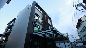 Een modern gebouw met een glazen ingang, een herkenbaar bord en een heldere lucht.
