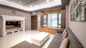Een moderne woonkamer met een open haard, bank, salontafel en kunstwerken aan de muren.