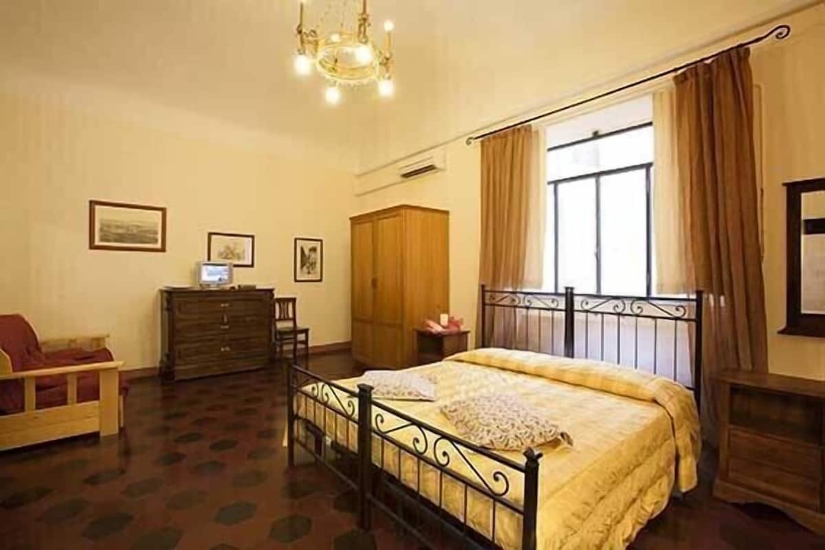 A bedroom with a bed, dresser, wardrobe, and a desk with a computer.