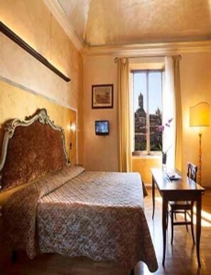 Habitación de hotel con una cama grande, un escritorio con silla, una ventana con vista a la ciudad y un cuadro en la pared.