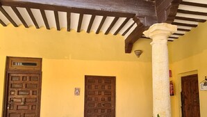 A courtyard with a tiled floor, wooden doors, and potted plants.