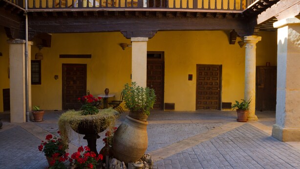 A courtyard with a tiled floor, potted plants, and a large urn.