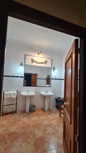 A bathroom with two sinks, a mirror, and a wooden door. - Casa Palacio Conde de Garcinarro (Huete)