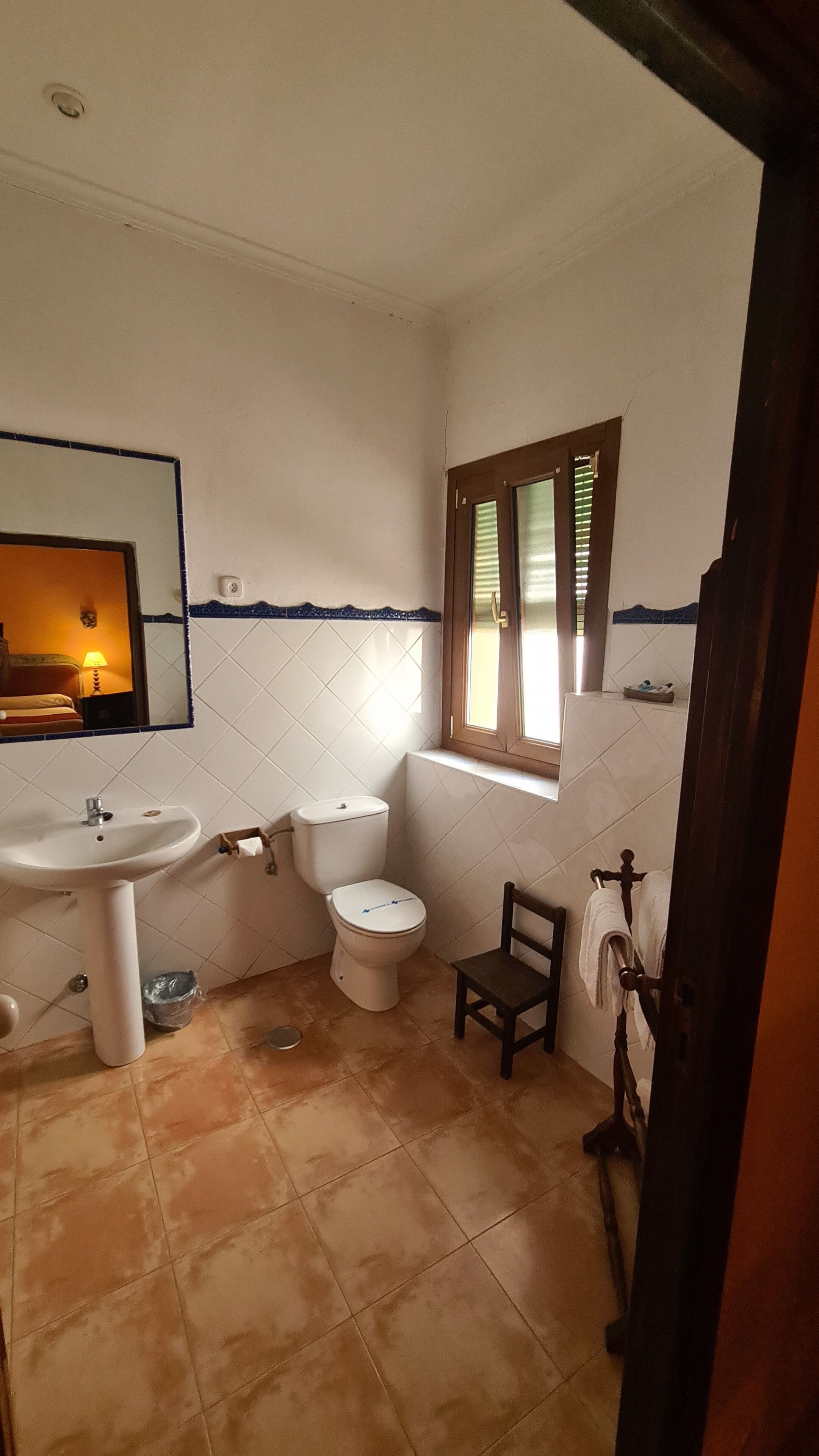 A small bathroom with a sink, toilet, and a window.