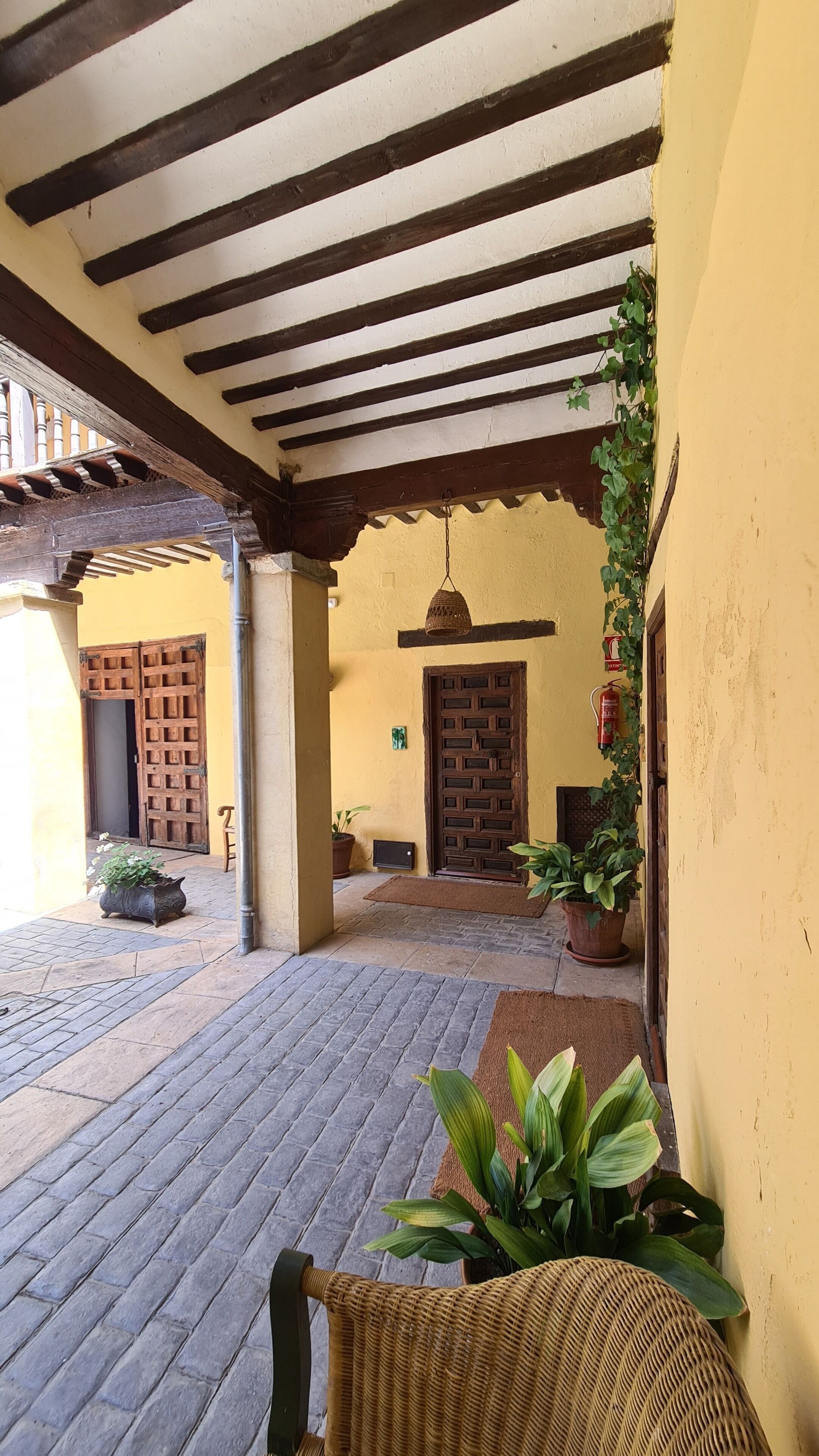Un espacio al aire libre techado con techo de madera, una puerta y plantas en macetas.