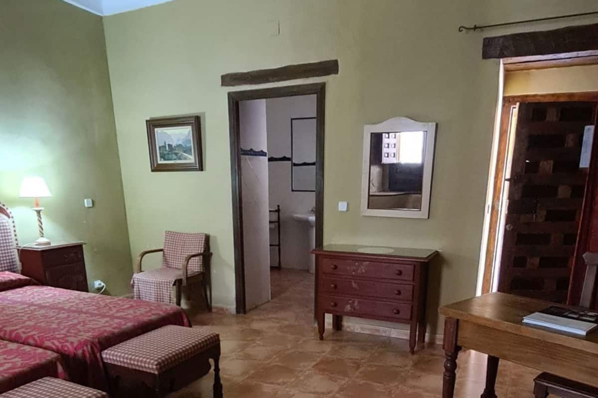 A room with a bed, a desk, a chair, and a small table.