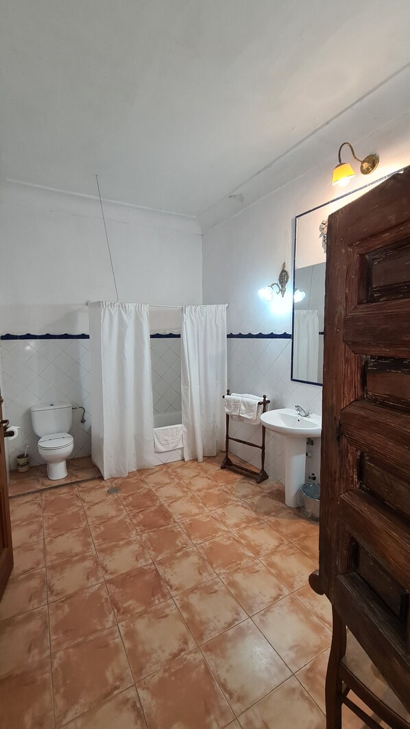 A bathroom with a toilet, sink, and shower area. - Casa Palacio Conde de Garcinarro (Huete)