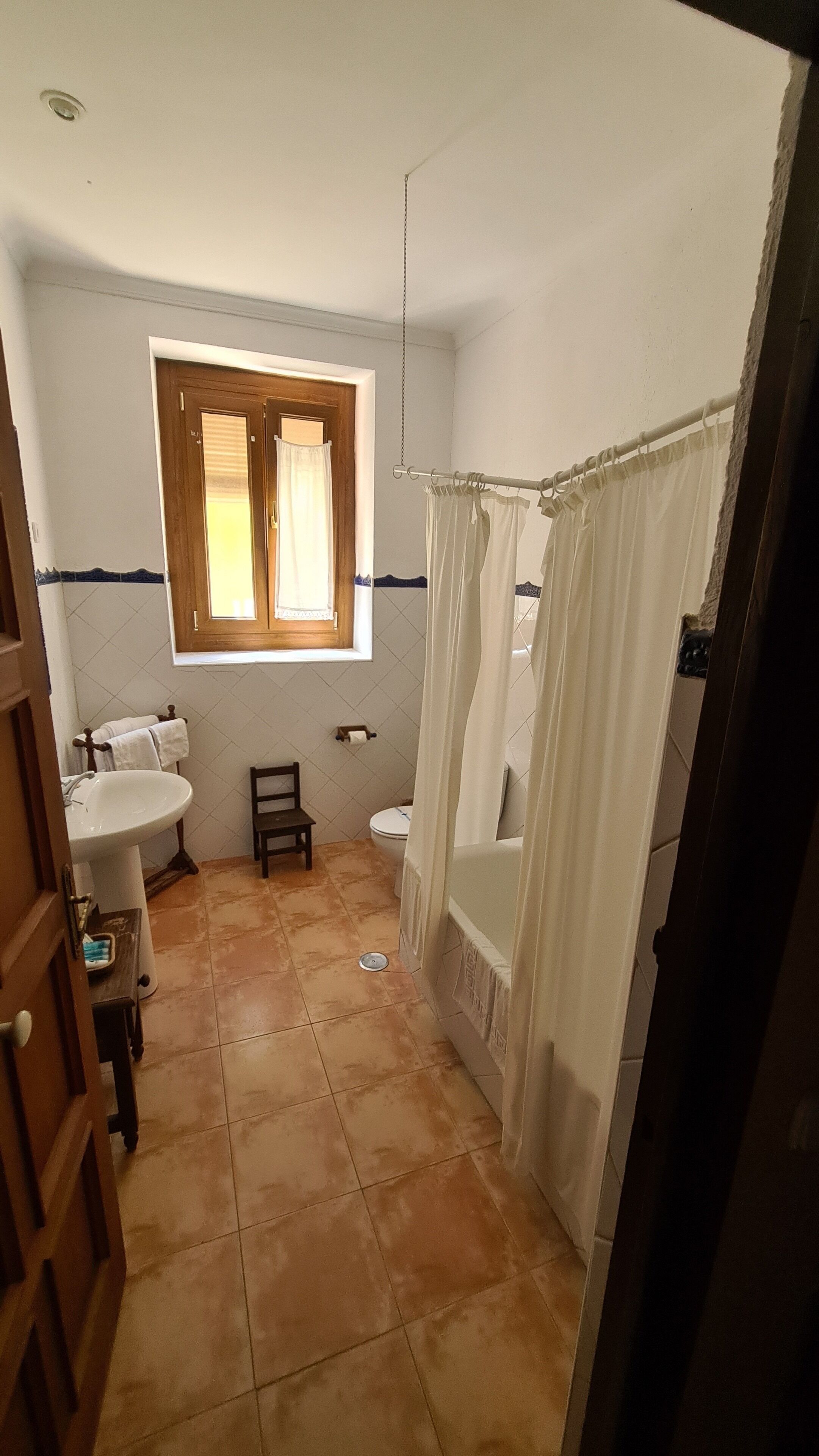 A bathroom with a window, a sink, a toilet, and a bathtub.