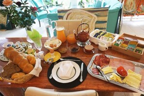 A breakfast spread with bread, eggs, cheese, ham, and juice on a wooden table. - Ferienhaus BLACK & WHITE (Bromberg)