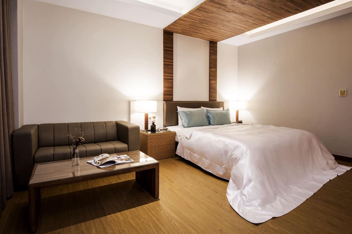 Habitació d'hotel amb llit, sofà, taulella de nit i taula de centre.