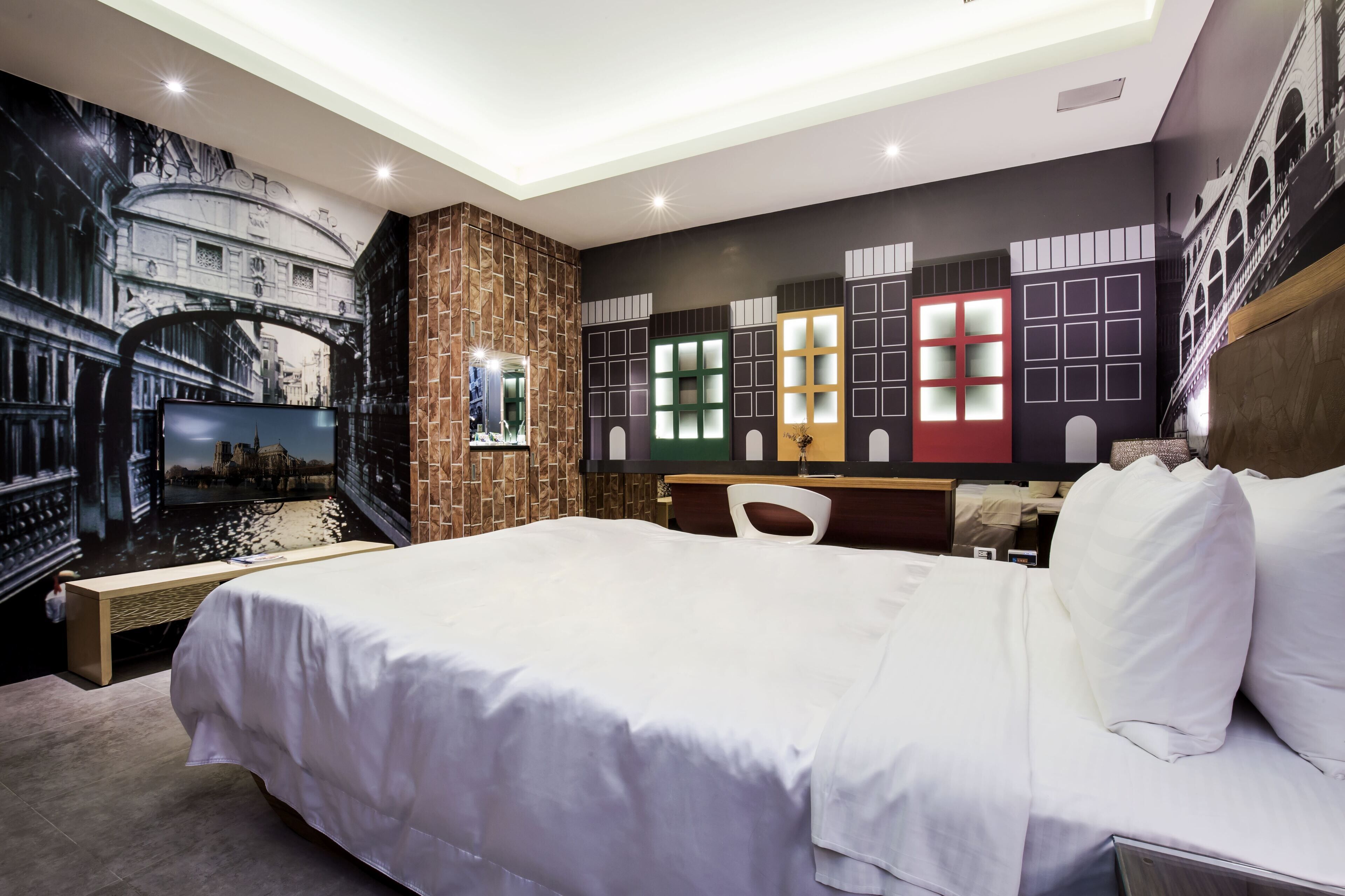 Une chambre d’hôtel avec un grand lit, un banc en bois, un bureau et une chaise.