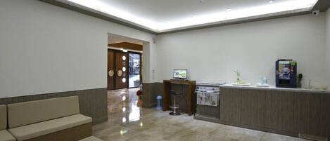 Un vestíbulo moderno con mostrador de recepción, zona de estar y una pequeña kitchenette.
