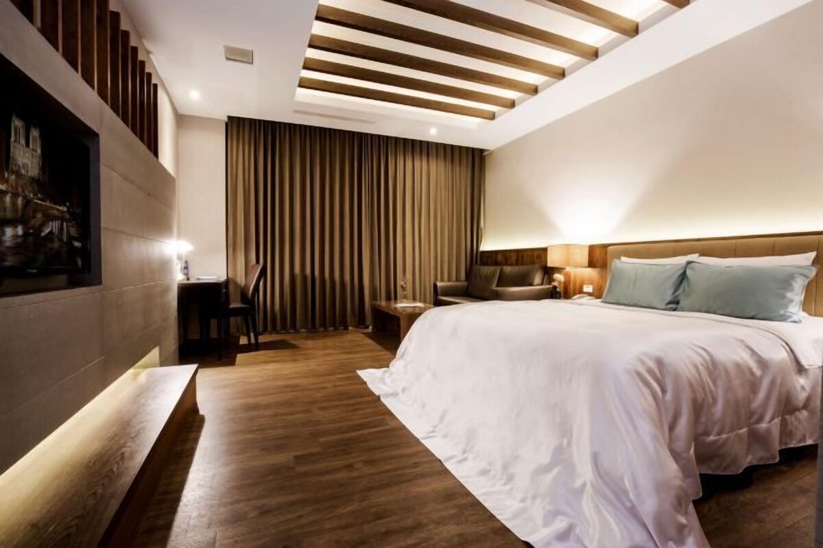 Una habitación de hotel moderna con una cama grande, un escritorio y una zona de estar.