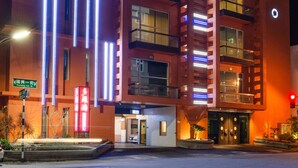Een motel met meerdere verdiepingen, verlichte reclameborden en verticale lichtstroken.