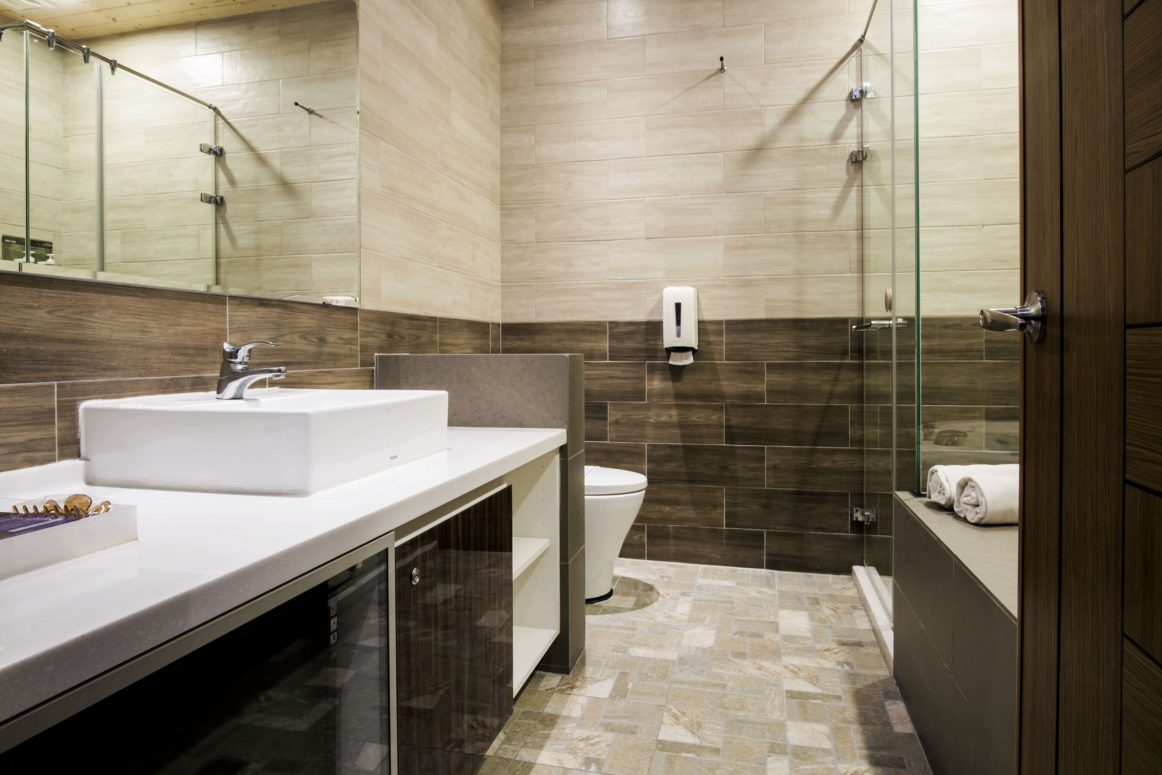 Een moderne badkamer met een witte wastafel, een douchecabine van glas en een toilet.