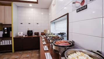 Uma mesa de buffet com diversos alimentos e utensílios de cozinha.