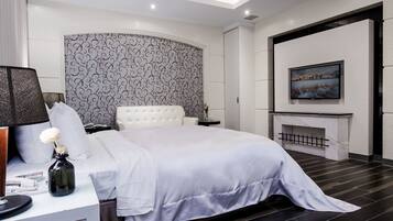 A modern bedroom with a large bed, a bedside table with a lamp, a decorative vase, and a fireplace.