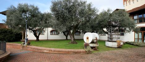 Un patio con sendero de ladrillo, árboles y una farola.