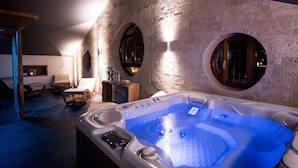 A spa room with a stone wall, a hot tub, and two wooden chairs. - Relais Santo Stefano (Sandigliano)