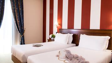 Una camera d'albergo con due letti, una testiera in legno, un comodino con una lampada e una finestra con tende.