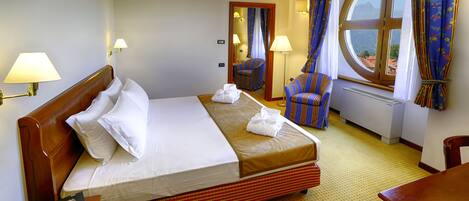 Habitación de hotel con una cama grande, una silla, un escritorio y una ventana con cortinas.