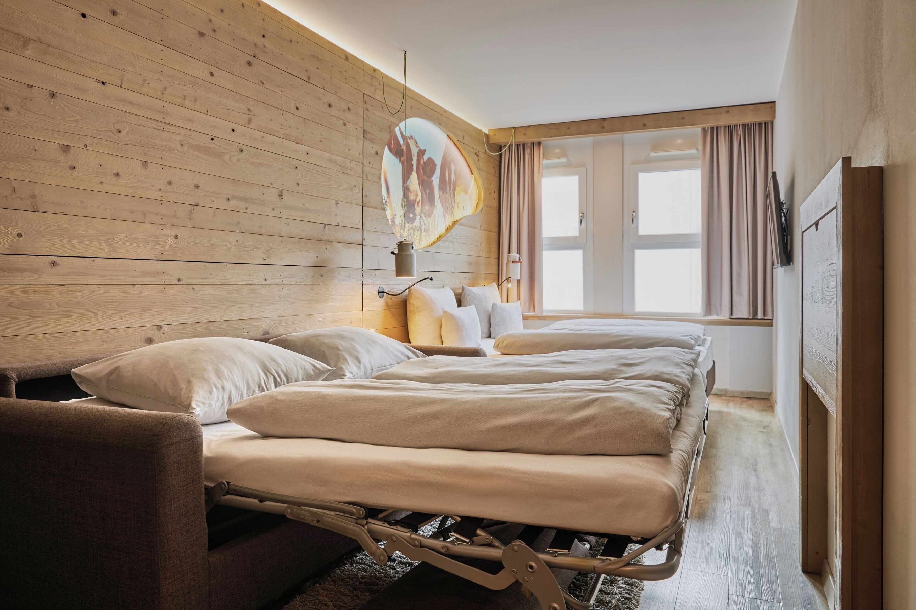 Une chambre avec un mur en bois, un lit avec une literie blanche, une table de chevet et une fenêtre avec des rideaux.