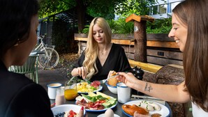 A group of people having breakfast outdoors with various dishes on the table. - Cocoon München Hauptbahnhof (Munich)
