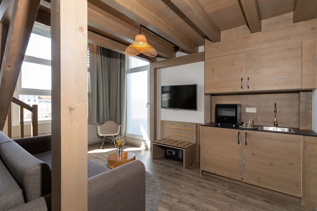 A modern kitchen with wooden cabinets, a built-in oven, and a flat-screen TV.