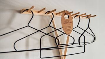 Un tendedero de madera con perchas negras y una etiqueta que dice "INSIDE COCOONING".