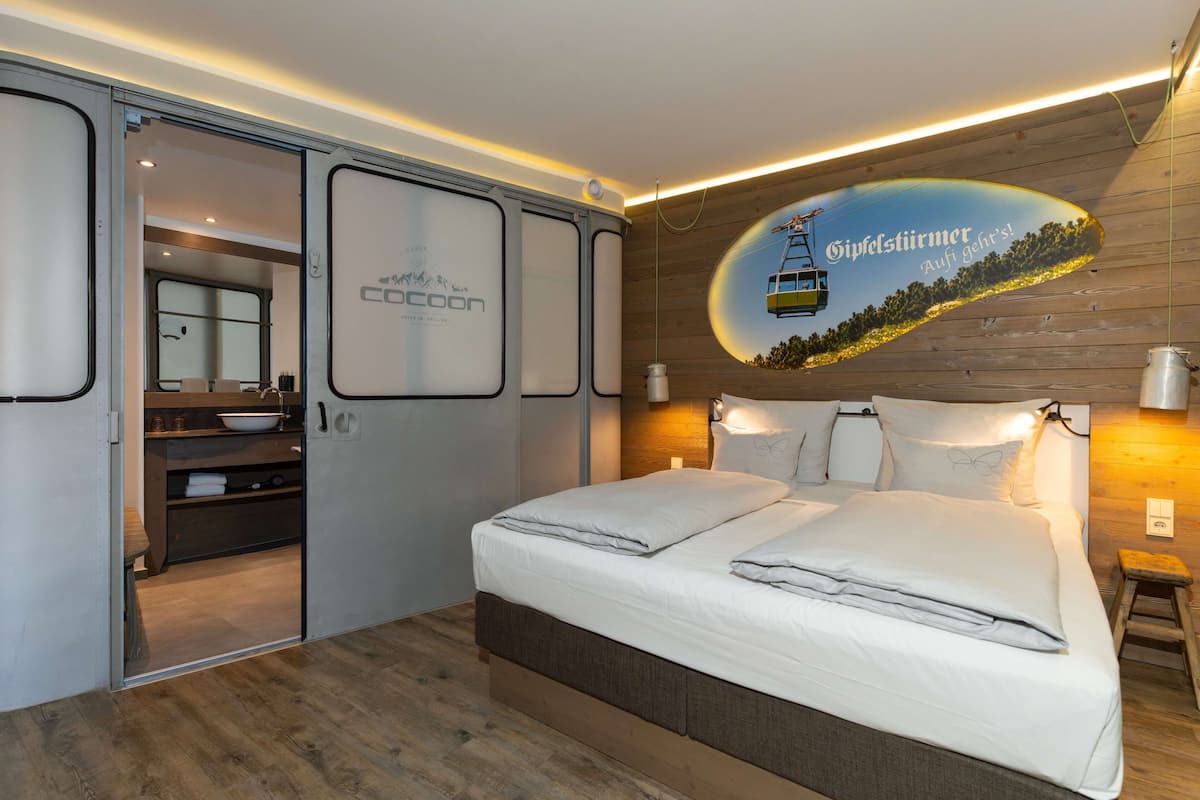 A modern bedroom with a bed, bedside tables, a mirror, and a wall-mounted artwork.