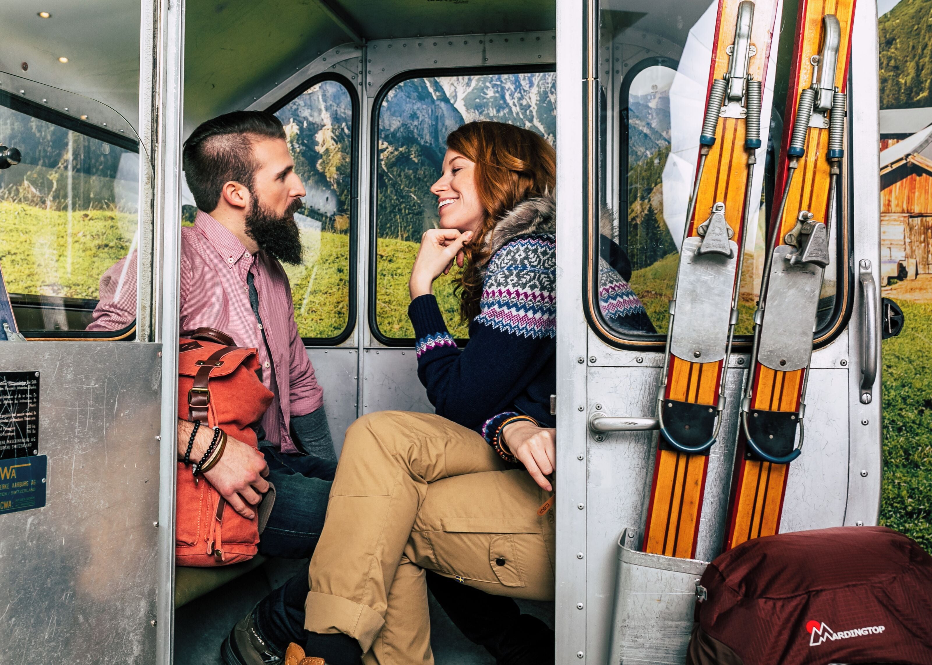Una pareja sentada dentro de un vehículo con vistas a un paisaje montañoso a través de la ventana.