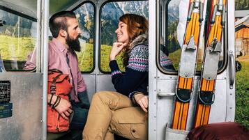 Una pareja sentada dentro de un vehículo con vistas a un paisaje montañoso a través de la ventana.
