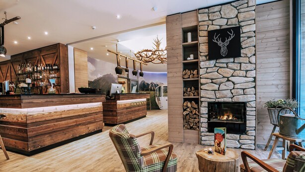 A modern bar area with wooden furnishings and a stone fireplace. - Cocoon München Hauptbahnhof (Munich)