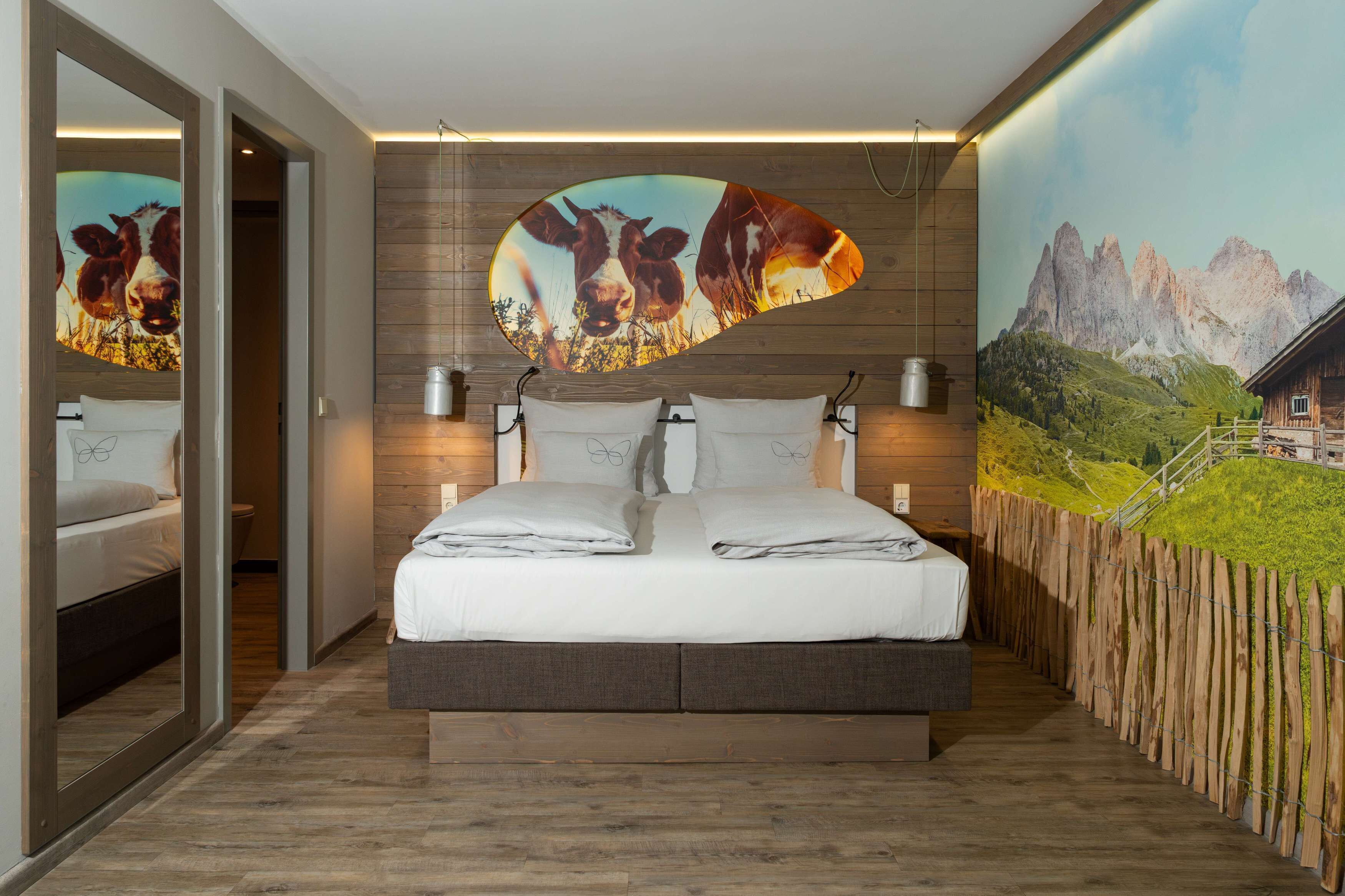 A bedroom with a bed, wooden walls, and a mountain landscape mural.