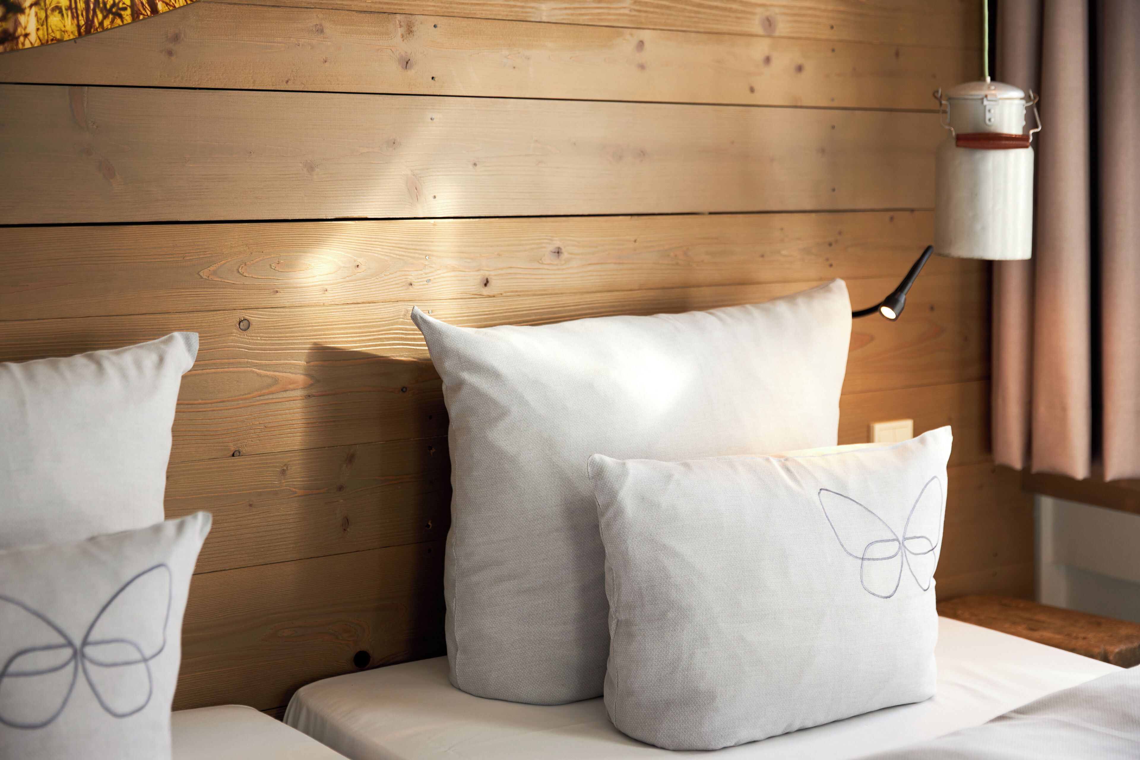 A wooden headboard with two pillows, one with a butterfly design.