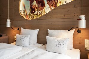 Ein Schlafzimmer mit Holzwänden, weißer Bettwäsche und zwei weißen Kissen mit Schmetterlingsmotiven.