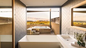 Une salle de bain moderne dotée d’une grande baignoire, d’un lavabo et offrant une vue sur un paysage pittoresque.