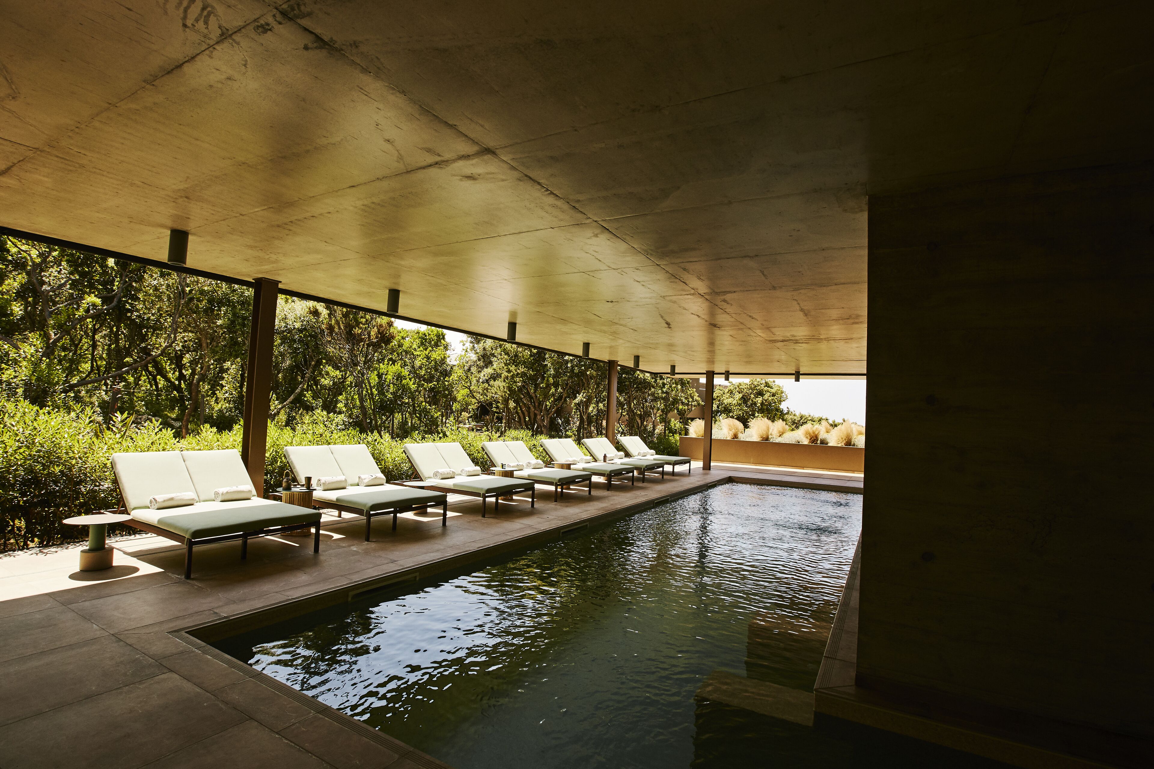 A pool area with lounge chairs and a covered walkway.