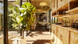 A modern interior with a wooden reception desk, potted plants, and a large painting on the wall. - Hôtel et SPA Version Maquis Citadelle (Bonifacio)