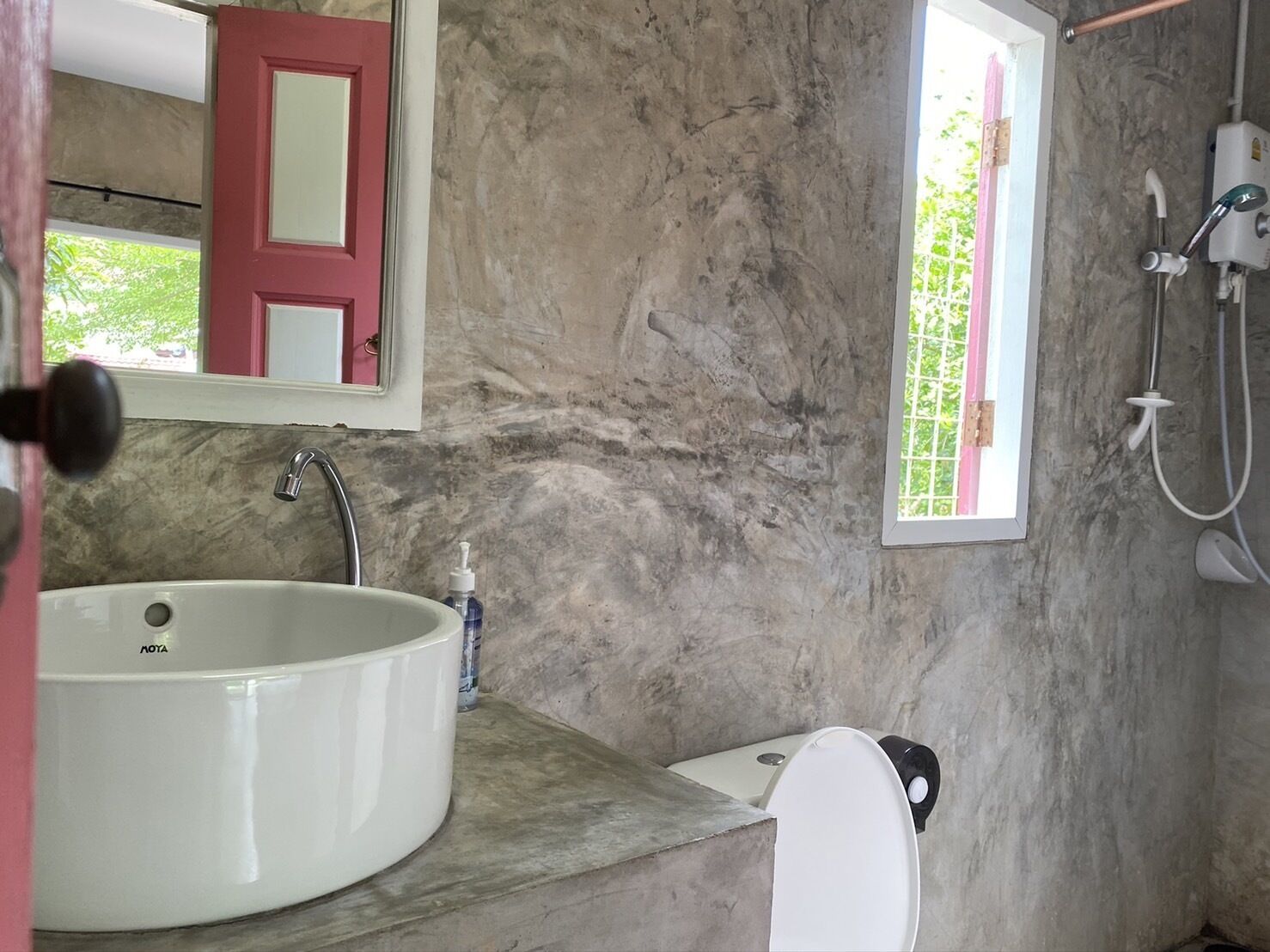 A bathroom with a large white sink, a toilet, a mirror, and a shower.