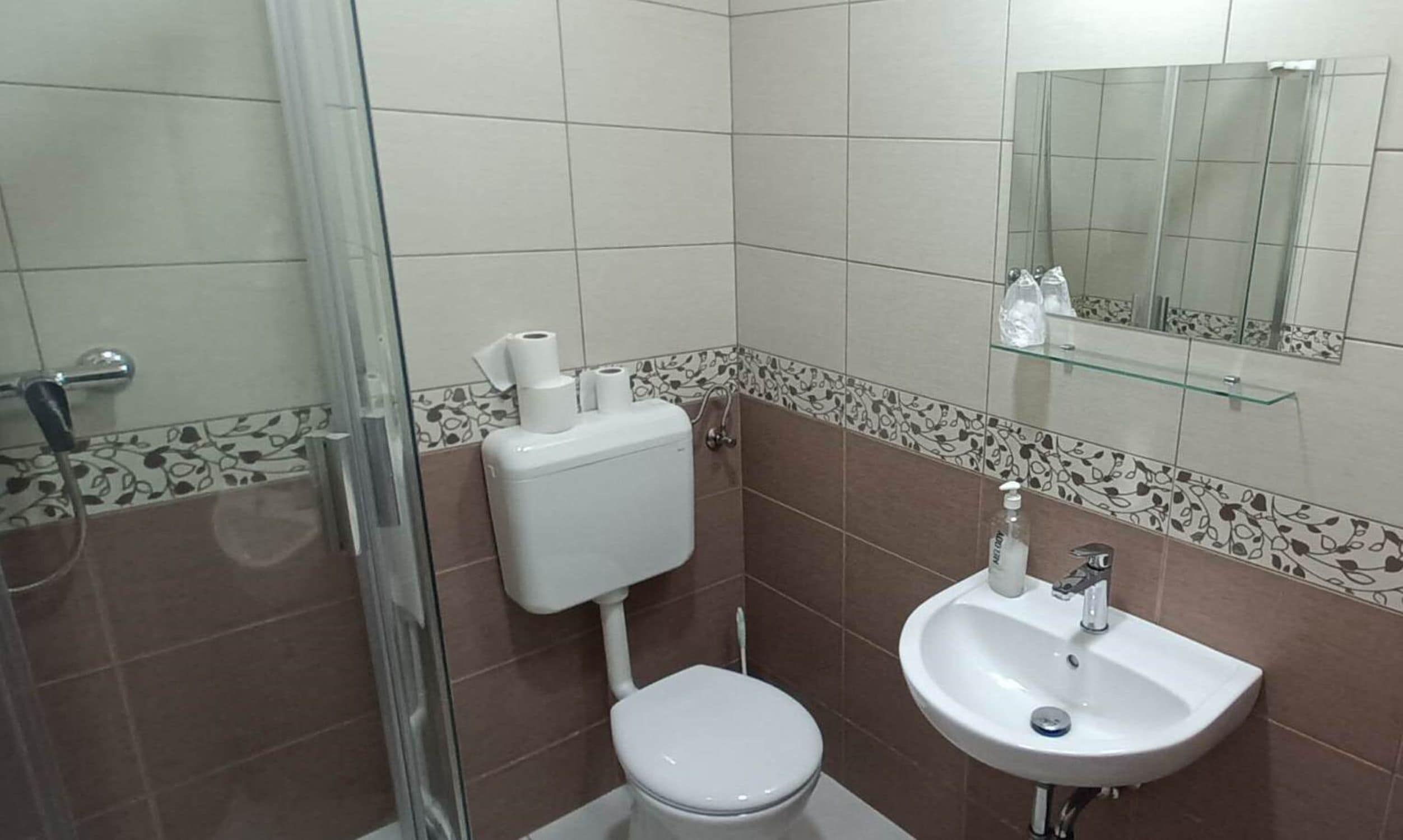 A small bathroom with a toilet, sink, and shower.