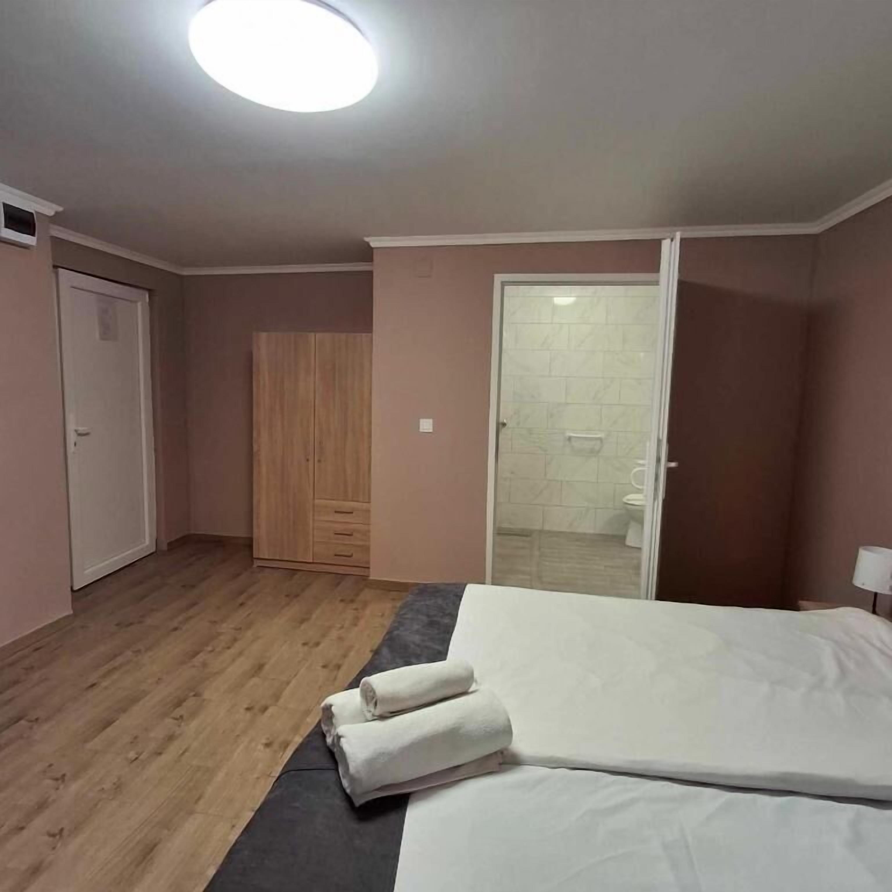 Une chambre à coucher avec un lit, une armoire et une salle de bain visible à travers une porte ouverte.