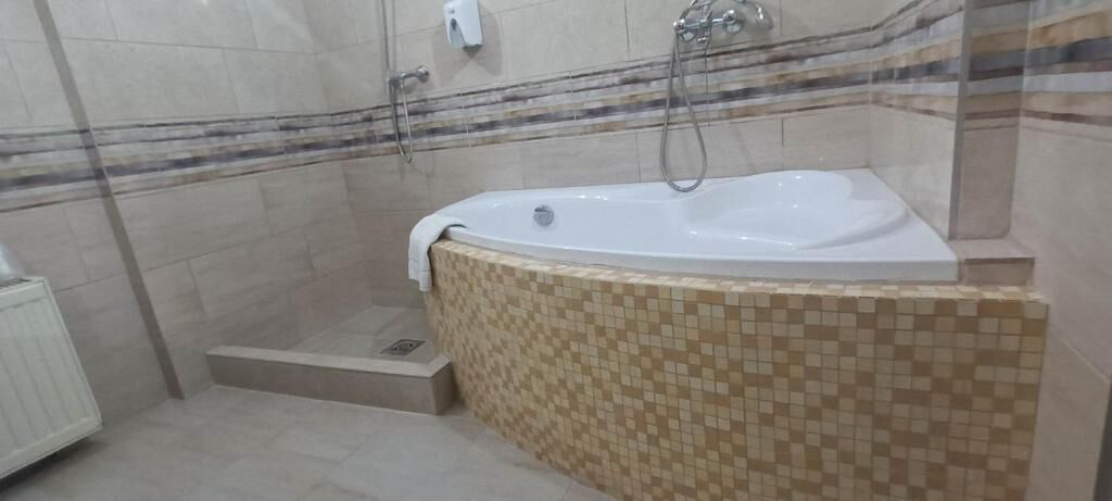 Een badkamer met een vrijstaand bad, een douchegedeelte en betegelde wanden.