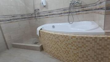 Een badkamer met een vrijstaand bad, een douchegedeelte en betegelde wanden.