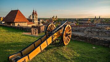 A historical cannon on display, with a stone wall and a church in the background.