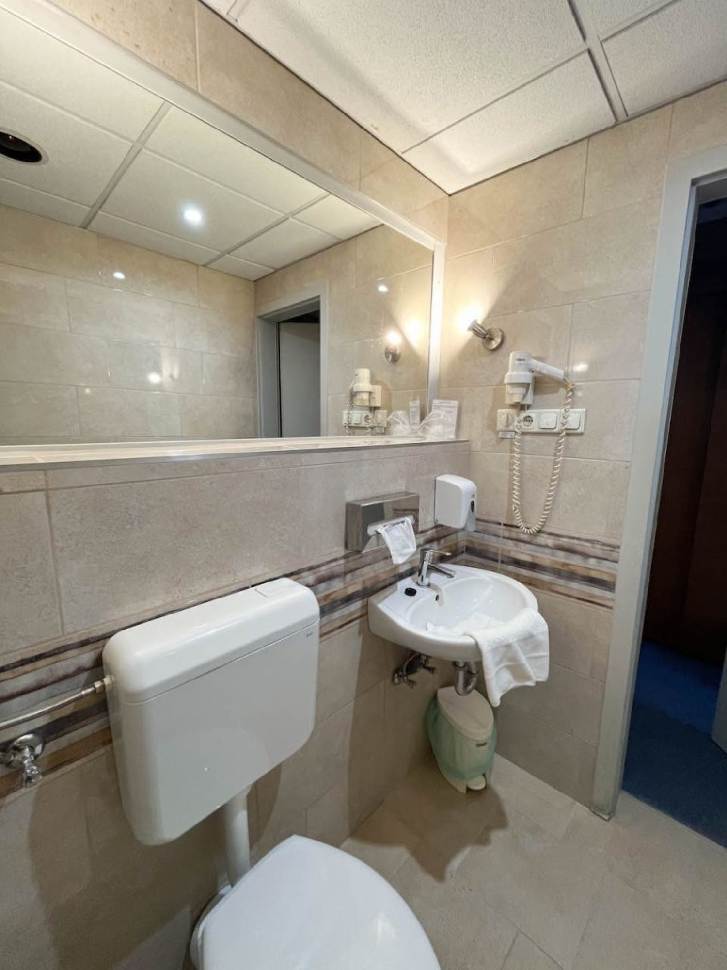 Un baño moderno con inodoro, lavamanos y espejo.
