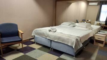 A hotel room with a bed, a chair, a desk, and a mirror.
