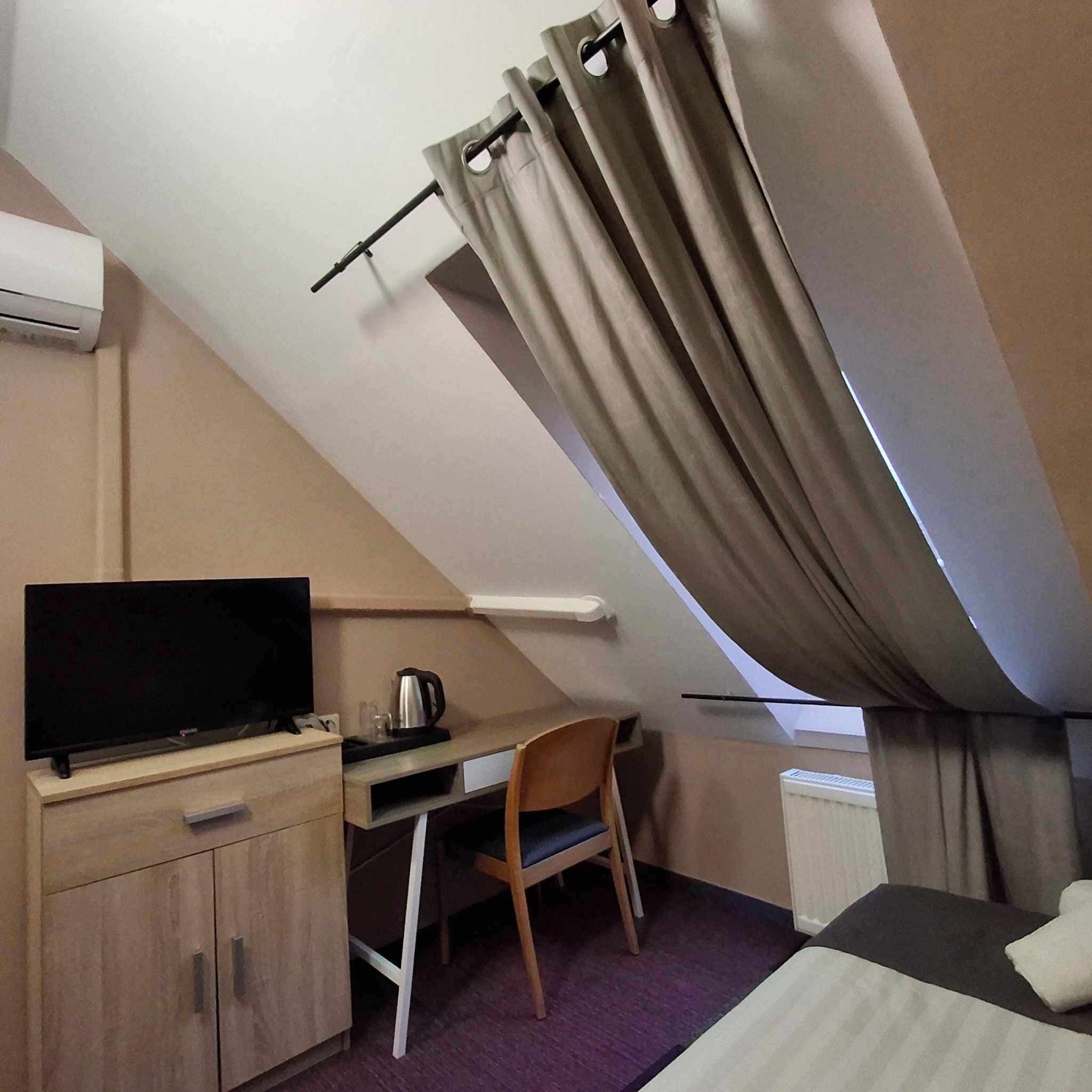 Una habitación pequeña y funcional con escritorio, silla y cama.